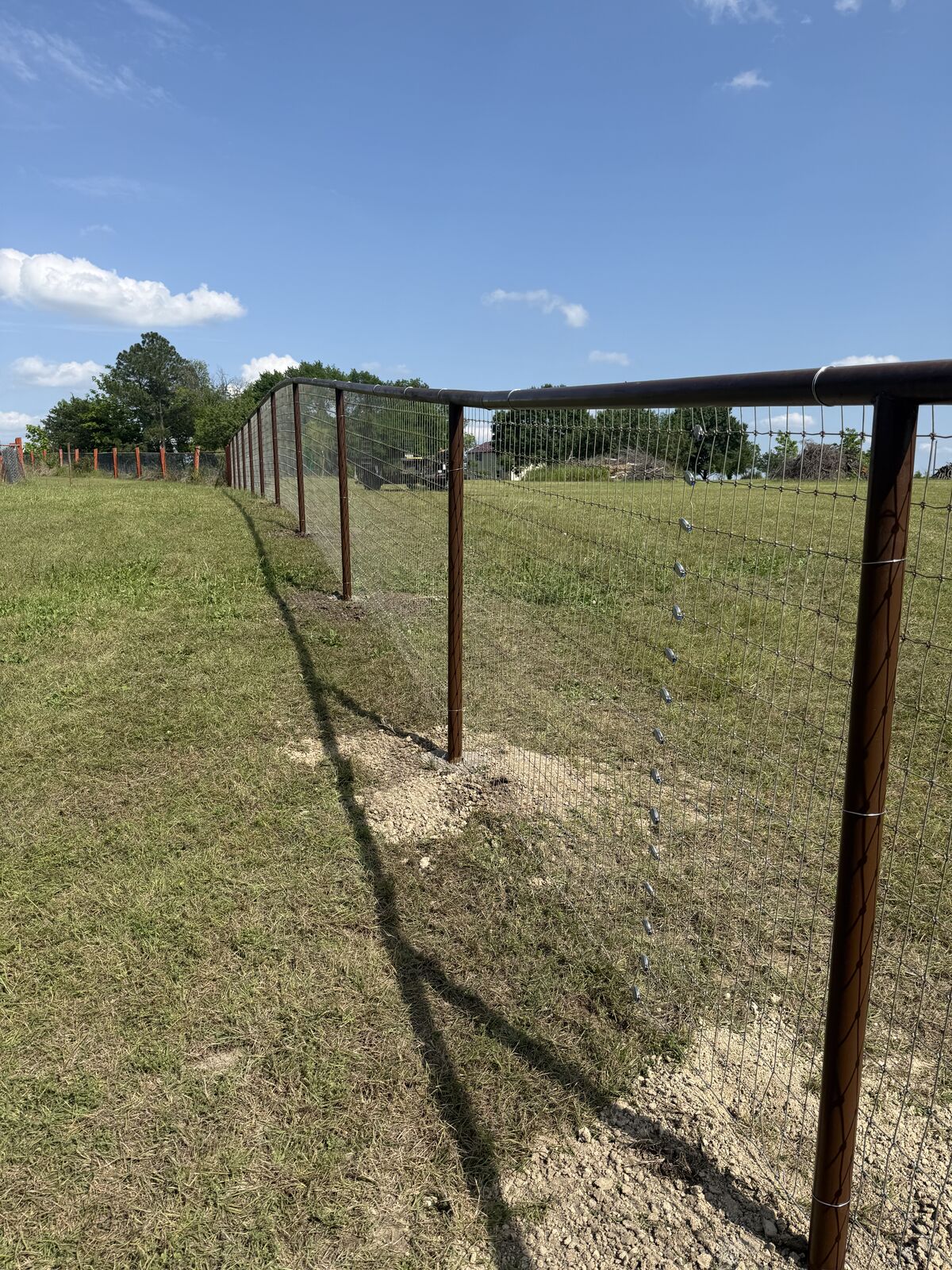Welded pipe corner brace on a new wire fence across a hillside