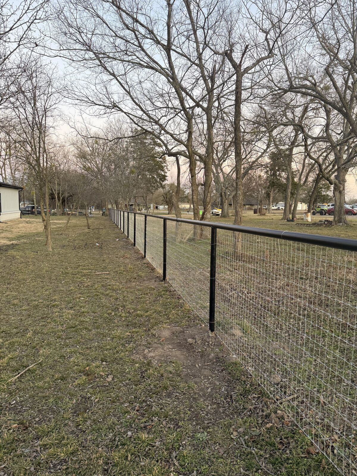 Pipe and net wire fence running along a wooded property line